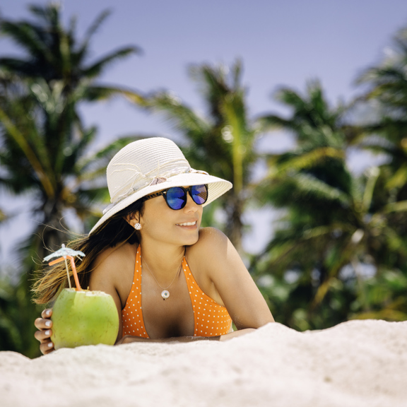 Femme sur la plage avec un cocktail à la noix de coco