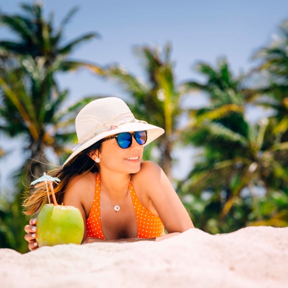 Femme sur la plage avec un cocktail à la noix de coco