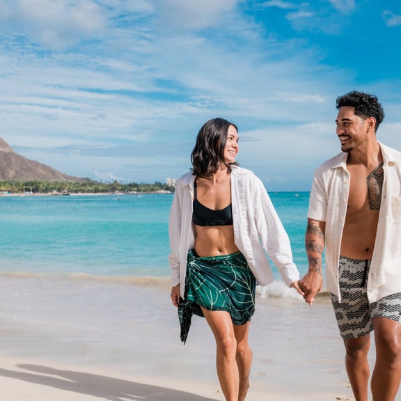Couple holding hands on Waikiki Beach with Diamond Head in the background
